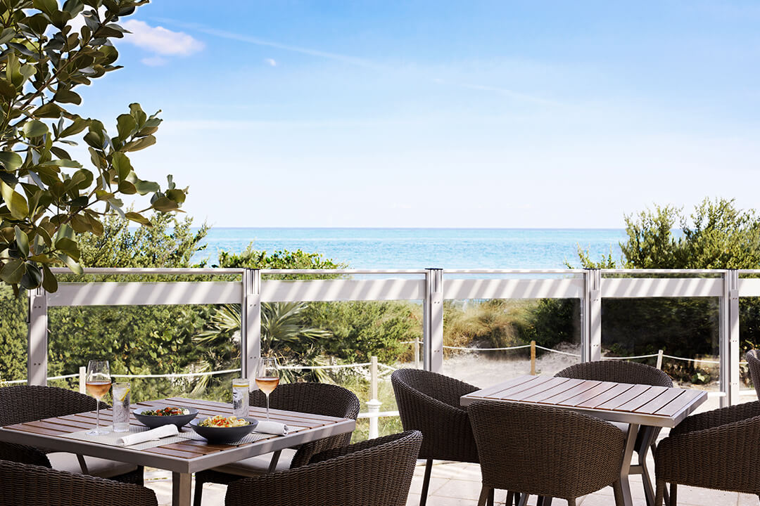 Two tables with outdoor seating and ocean view