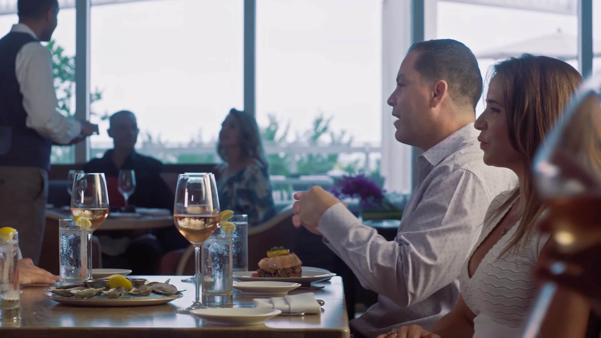 a couple sitting at a table with wine and food