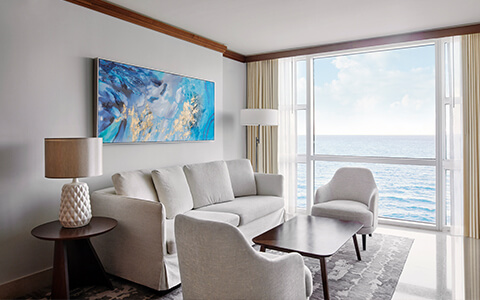 a neutral living room with a view of the water outside.