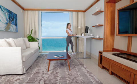 woman with glasses at standing desk in apartment in front of a computer