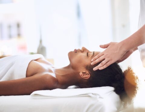 a lady receiving a massage on her head, hands placed on her head