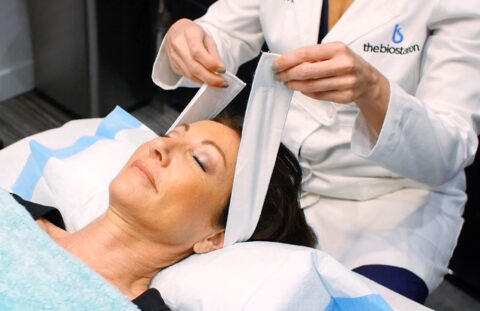 woman lying down with a doctor wrapping her head for a treatment