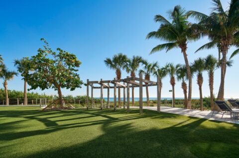 Image of the North Tower Lawn, which includes a large grass area, palm trees, wooden wedding arbor and an ocean view