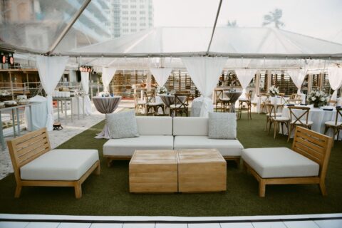 A bohemian-themed wedding celebration at the North Tower Lawn, with white drapes, cushioned wooden furniture and stand-up tables