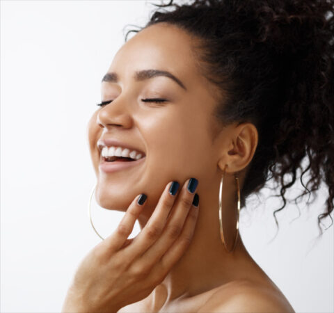 girl with eyes closed, smiling with her hand on her neck
