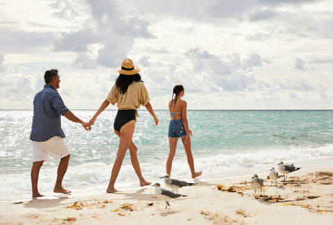 family walking on the beach with blue water in the backgorund