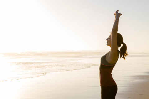 woman stretcthing on the beach at sundown